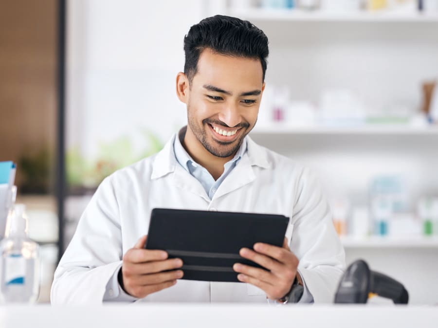 A pharmacist using an assistant on a tablet at the counter