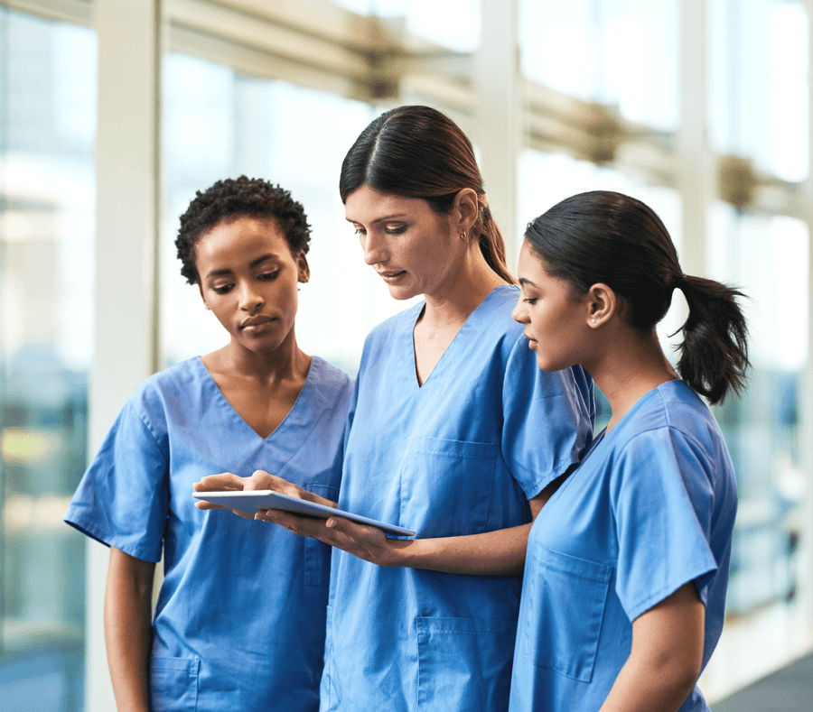 Three clinicians reading a tablet together in a corridor