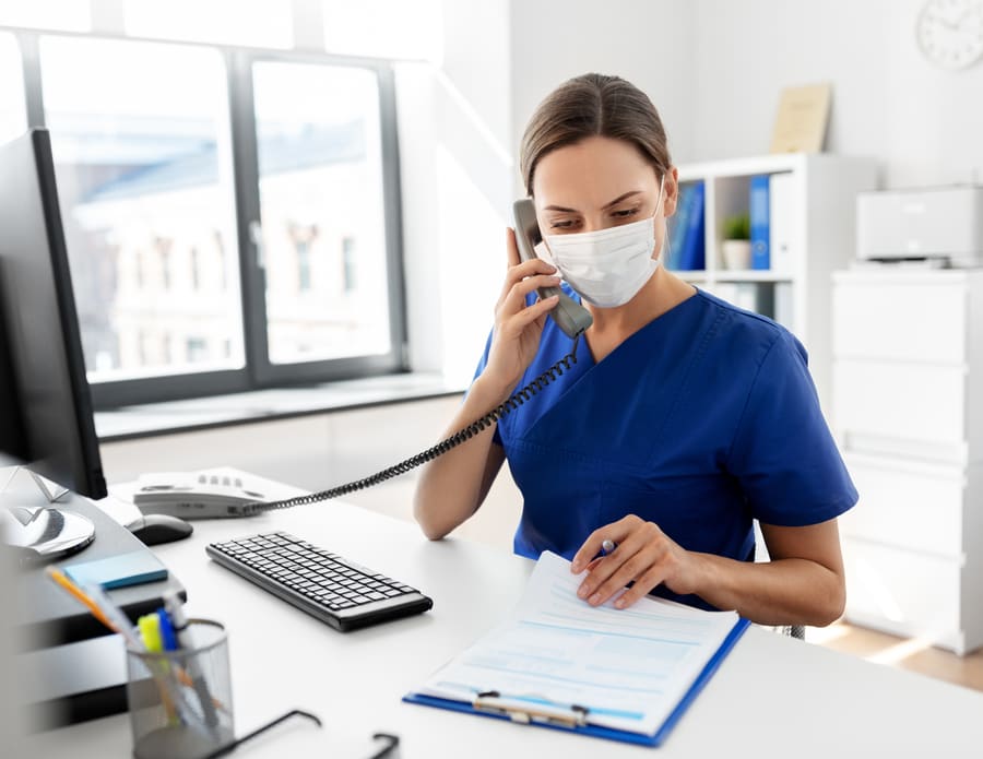 A clinician on the phone at a desk, a form in front of them