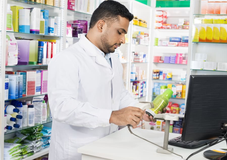 A pharmacist scanning a product at the counter