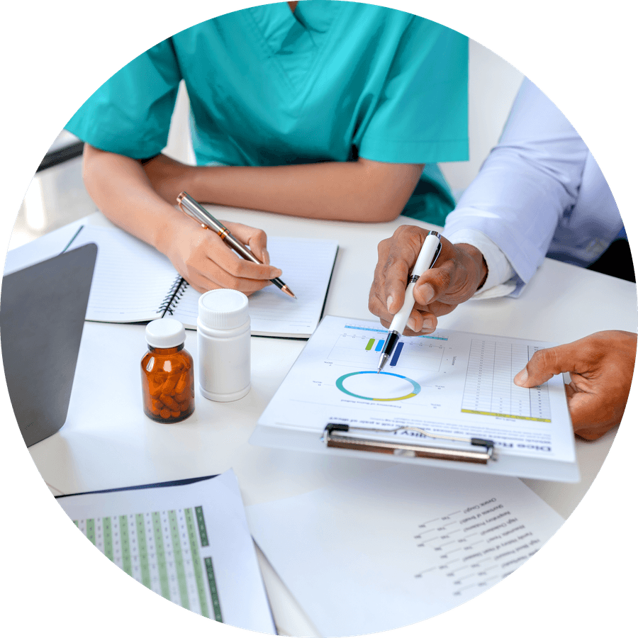 Two colleagues working through a printed assessment, medication bottles on the desk