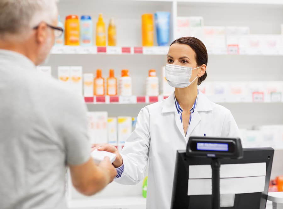A pharmacist handing a prescription across the counter