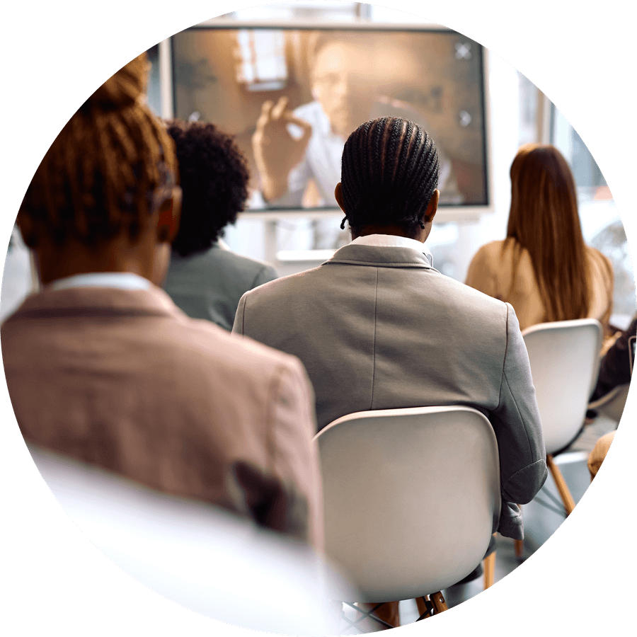 An audience watching a presenter on a wall screen