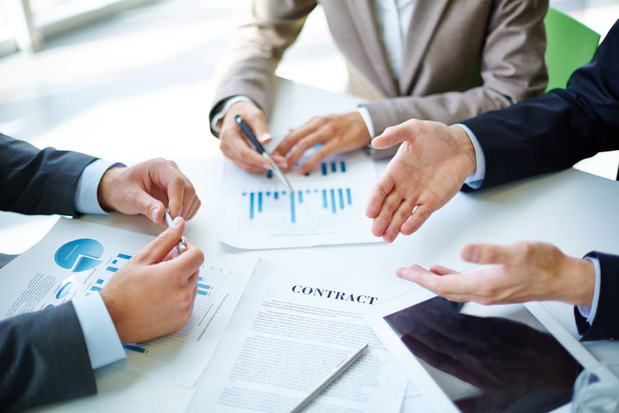 Two colleagues going over a printed sales chart and a contract