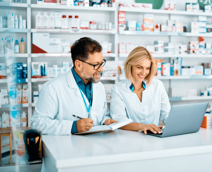 Two pharmacists working at a laptop behind the dispensary counter