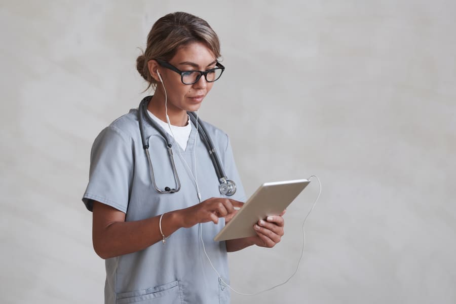 A clinician in scrubs dictating notes into a tablet