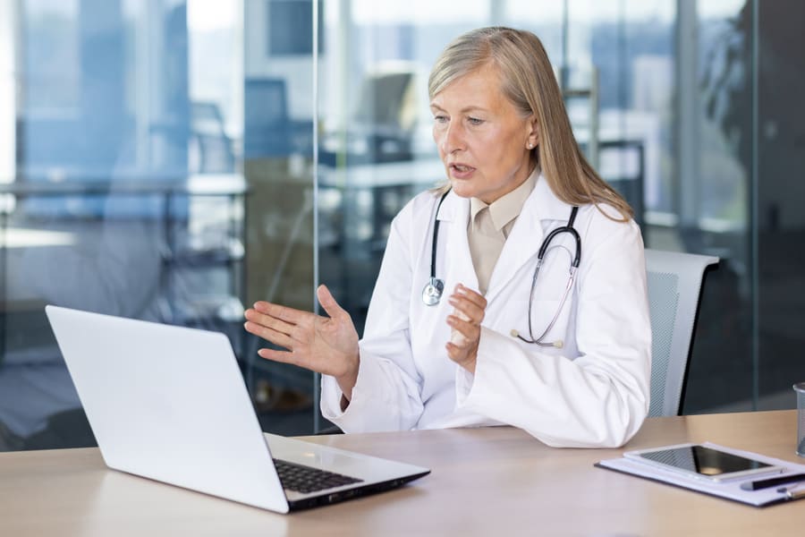 A clinician talking through a consultation on a laptop