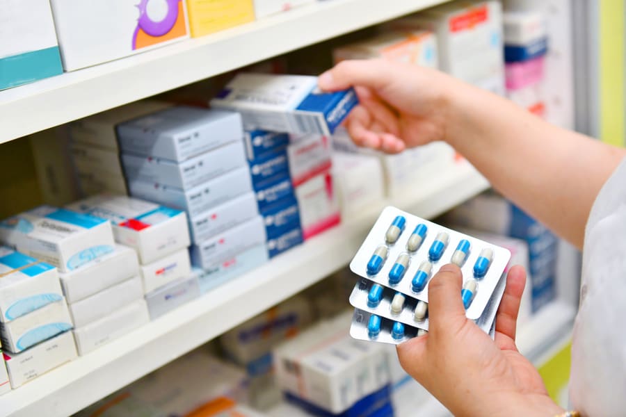 A hand taking a product box from a stocked retail shelf